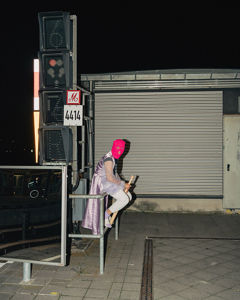 Den Kiez korrigieren Eine Person mit Wrestlingmaske sitzt an einer Bahnstation