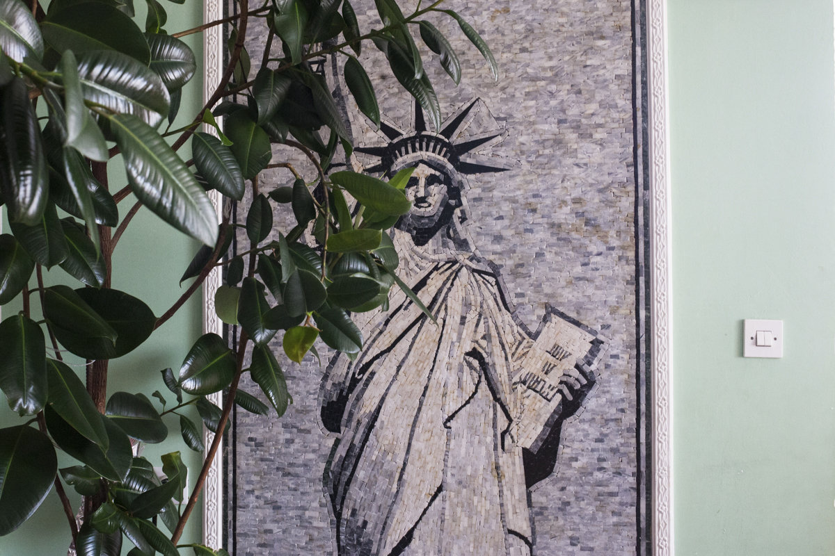 Ein Mosaik zeigt eine Freiheitsstatue auf einer grünen Wand