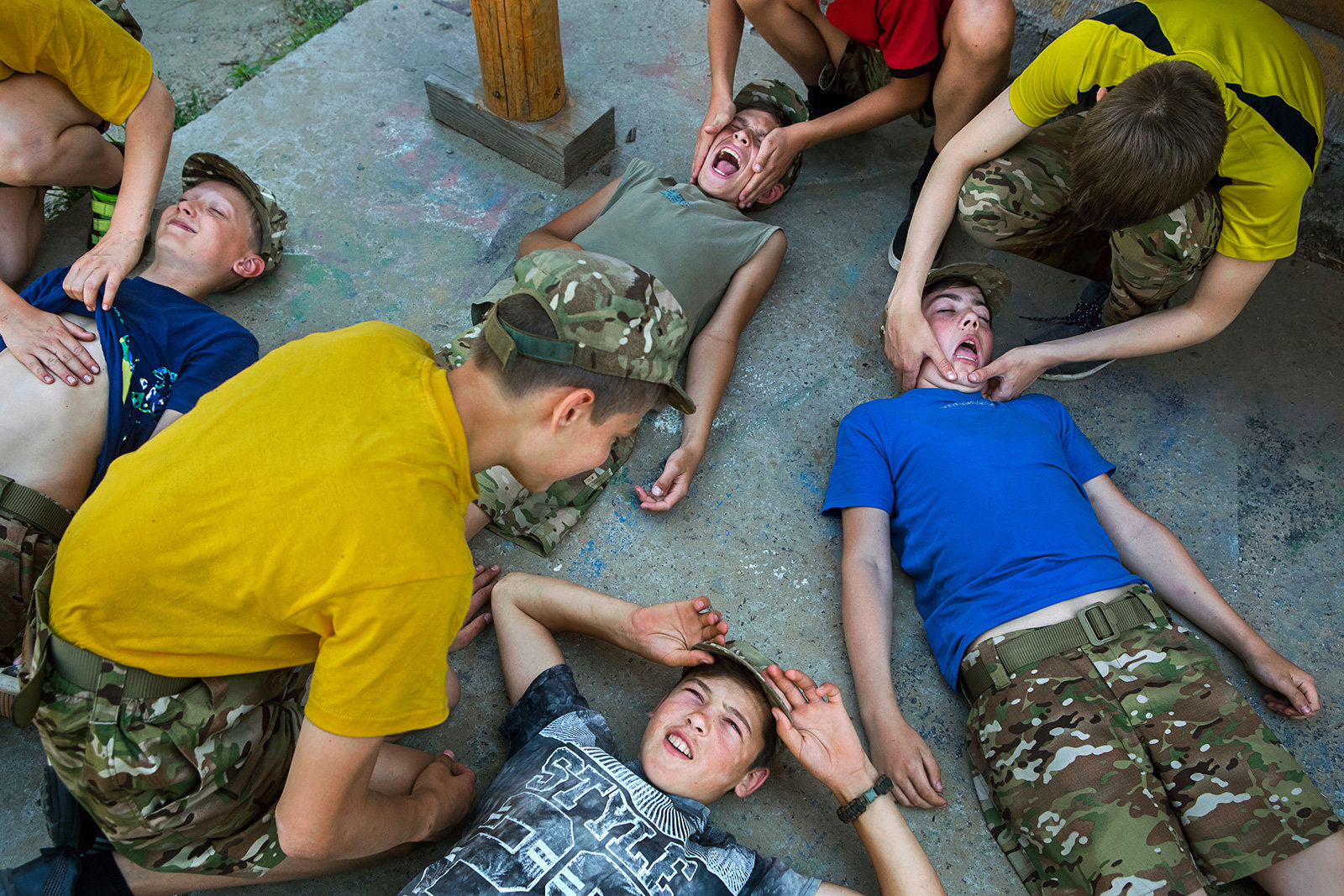 Kinder in Militärkleidung liegen auf einem Betonboden