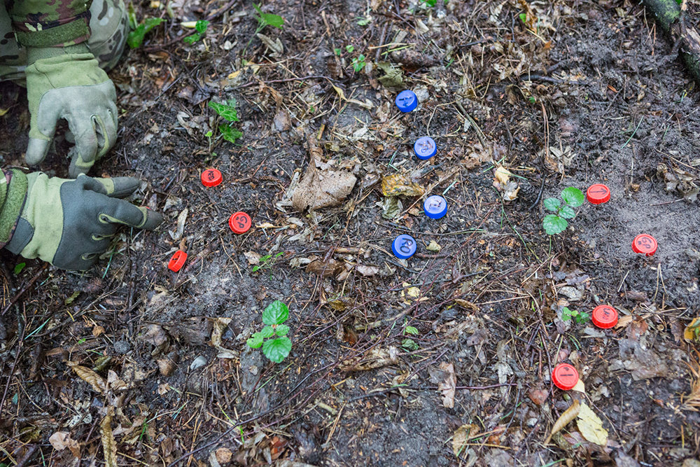 Taktik ist sehr wichtig. Mit Hilfe von Flaschendeckeln auf dem Waldboden wird sie vermittelt. So wird das Vorgehen gegen den Feind vorher geplant.