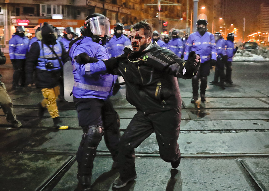 Demonstrant mit blutigen Gesicht wird von einem Polizisten festgehalten