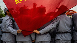 Raumfahrtarbeiter in Uniformen im Stil des Langen Marsches halten in Yan'an  eine Flagge