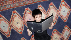 Eine Frau hält ihren Laptop wie ein Buch und liest darin