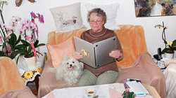 Alte Dame hält einen Laptop wie ein aufgeschlagenes Buch