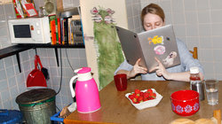 Eine Frau sitzt in der Küche und liest im Laptop