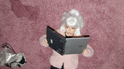 Mädchen mit Perücke liest im Laptop
