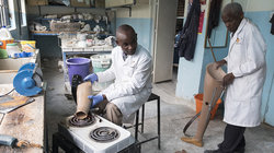 Um die Beinprothese mit dem künstlichen Fuß zu verbinden wird das untere Ende des modifizierten Plastikrohrs auf einer Herdplatte erhitzt. Noch heiß wird es auf den Fuß gestülpt und nach dem Erkalten mit Schrauben fixiert