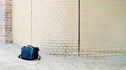 Herrenlose Reisetasche vor Ziegelwand; Foto: Johannes Heinke