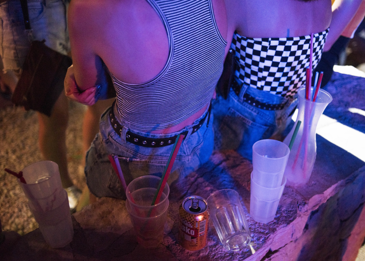 Zwei Mädchen sitzen auf einer Mauer auf der leere Drinks stehen
