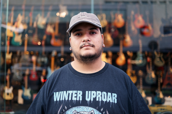 Lidor Kalai steht vor einem Schaufenster voller Gitarren Lidor Kalai steht vor einem Schaufenster voller Gitarren