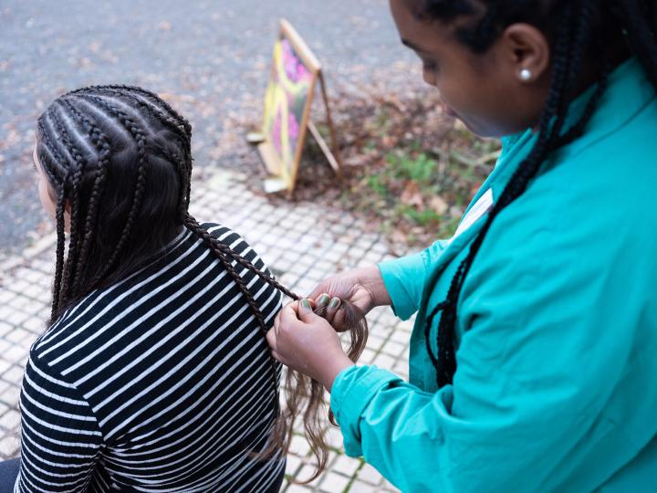 Eine Frau bekommt vor dem Salon die Haare geflochten Eine Frau bekommt vor dem Salon die Haare geflochten