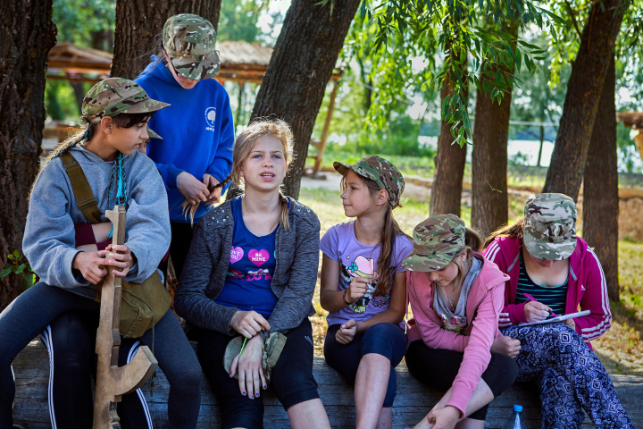 Girls participating to the ultra-nationalistic Azovets children's camp are sitting together, chatting and taking care of each other's hair, after a long day of training on the banks of the Dnieper river, in Kiev, Ukraine's capital.
