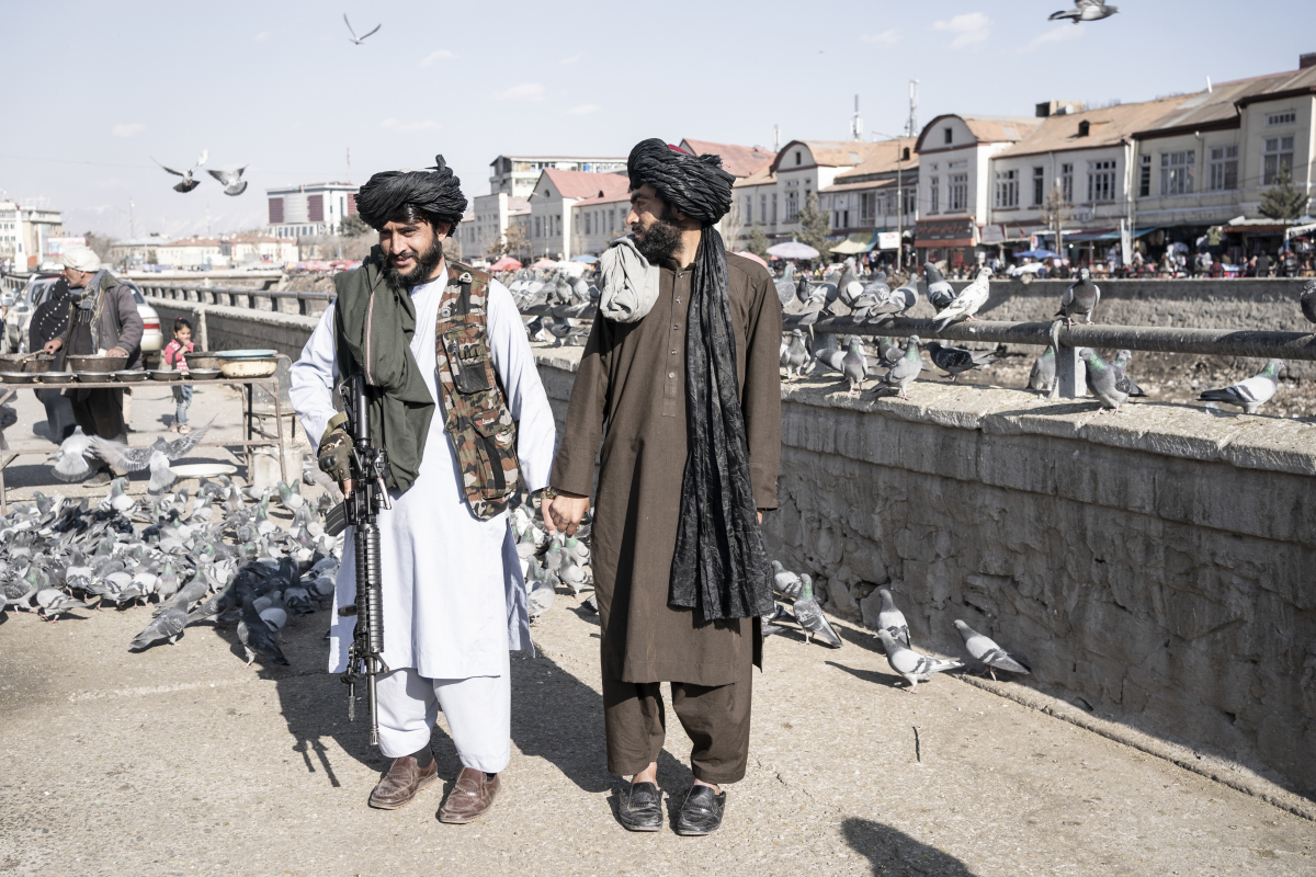 Zwei bewaffnete Taliban lassen sich Händchen haltend auf einer Brücke voller Tauben fotografieren Zwei bewaffnete Taliban lassen sich Händchen haltend auf einer Brücke voller Tauben fotografieren