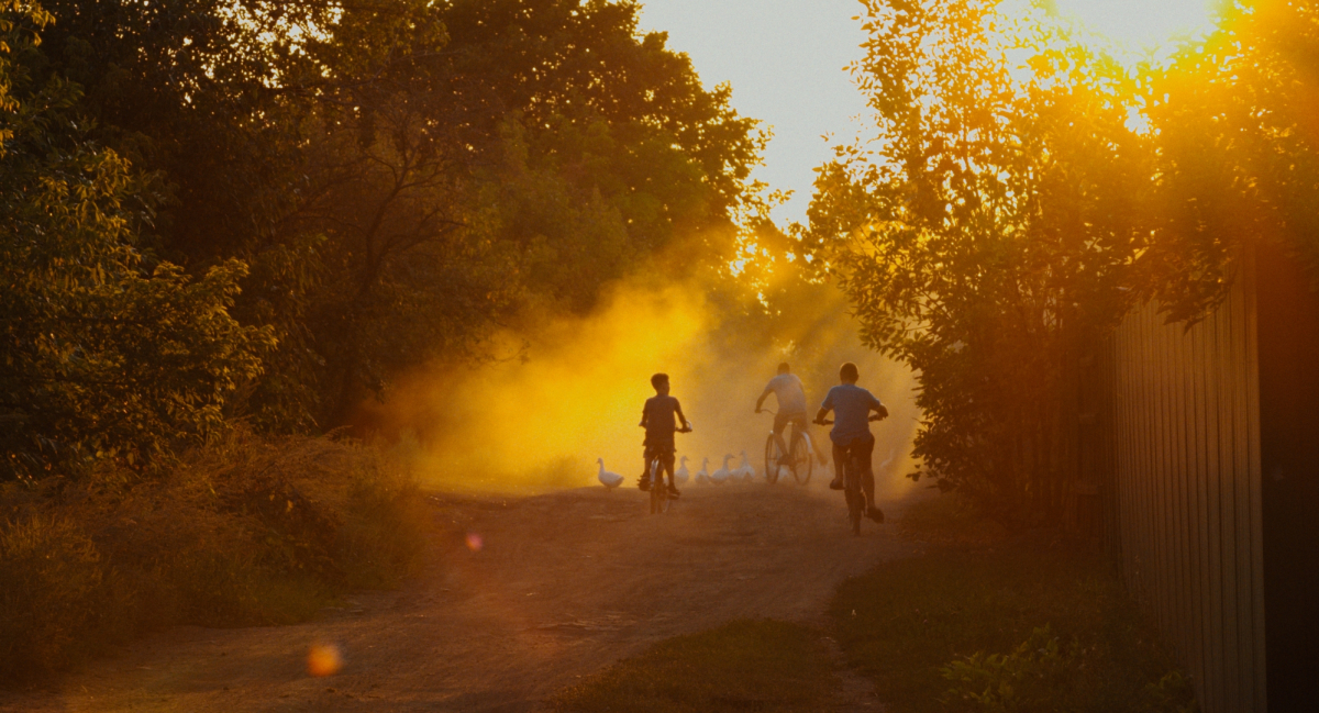 Drei Kinder fahren auf Fahrrädern in den Sonnenuntergang