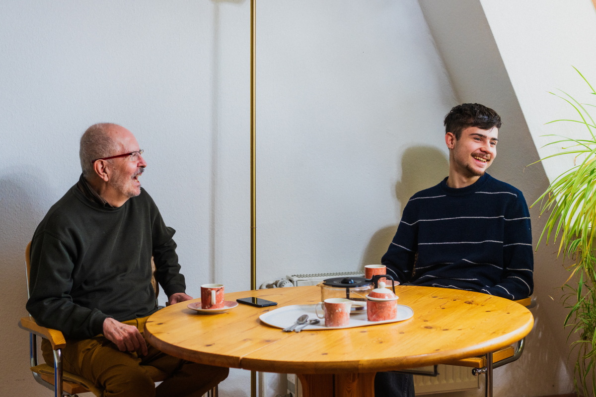 Matthias Reich und Johannes Preißler sitzen lachen am Esstisch