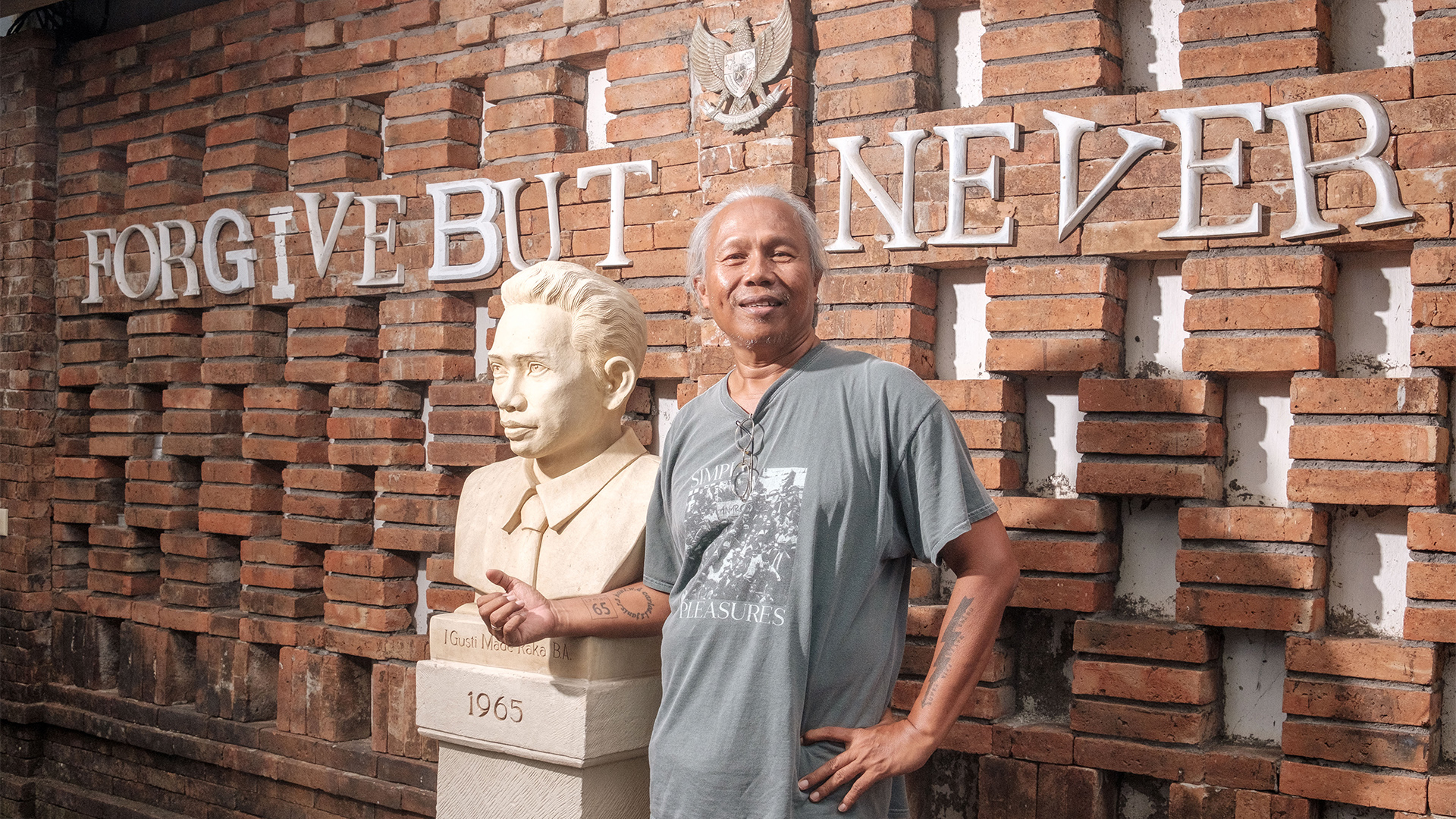 Agung Alit neben der Büste seines Vaters