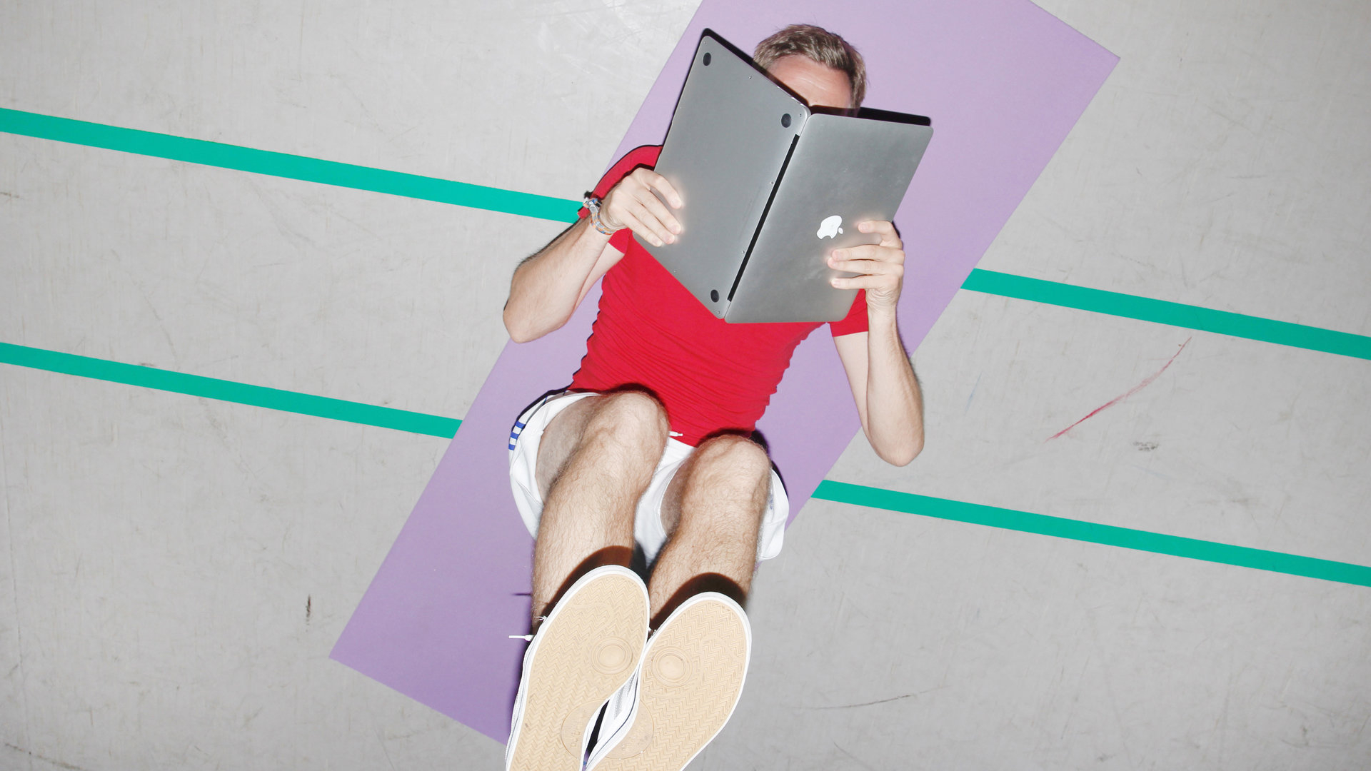 Mann liegt auf der Yoga-Matte und liest im Laptop Mann liegt auf der Yoga-Matte und liest im Laptop