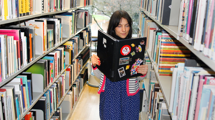 Fraus in einer Bibliothek liest in ihrem Laptop