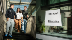 Artur, Can und Hanin auf der Treppe der Schule / "Ruhe Bitte" Zettel an einer Glastür