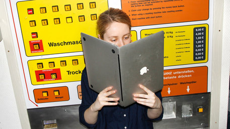 Frau im Waschsalon liest in ihrem Laptop