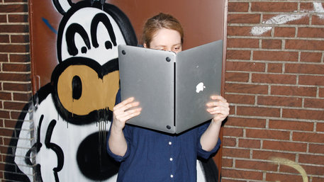 Ein Mädchen liest in einem Laptop, als wäre es ein Buch