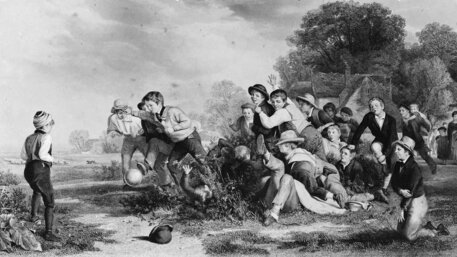 Eine Gruppe von Jungen spielt eine altmodische Version des Fußballs