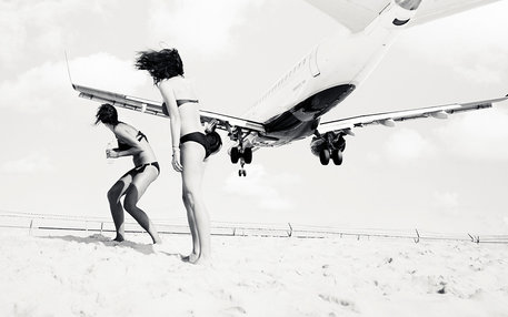 Tieffliegendes Flugzeug über zwei Frauen am Strand 