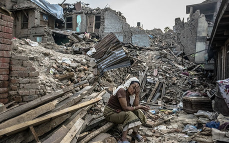 Nach dem schweren Erdbeben sitzt eine nepalesische Frau zwischen den Trümmern ihres Dorfes