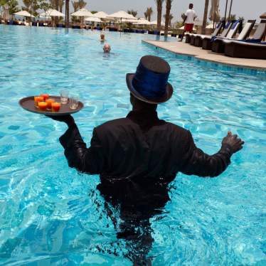 Kellner in Smoking serviert Drinks in einem Pool