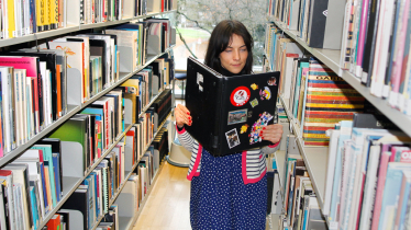 Fraus in einer Bibliothek liest in ihrem Laptop