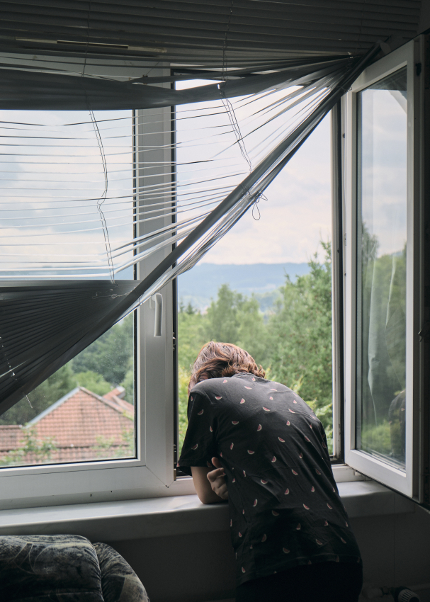 Kian schaut aus dem Fenster ihrer Wohnung